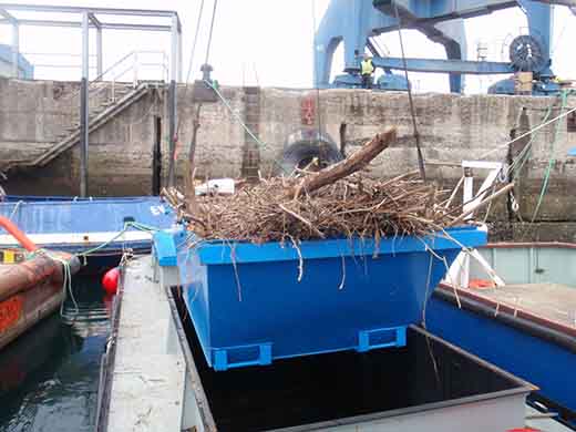 Descargando contenedor repleto de residuos recogidos en la superficie del agua con la grua de la Autoridad Portuaria de Bilbao