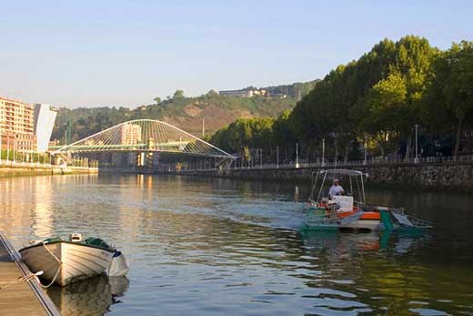 Urgarbi 2000 con las cestas semi elevadas navega por la Ría de Bilbao con el puente Zubi Zuri de fondo